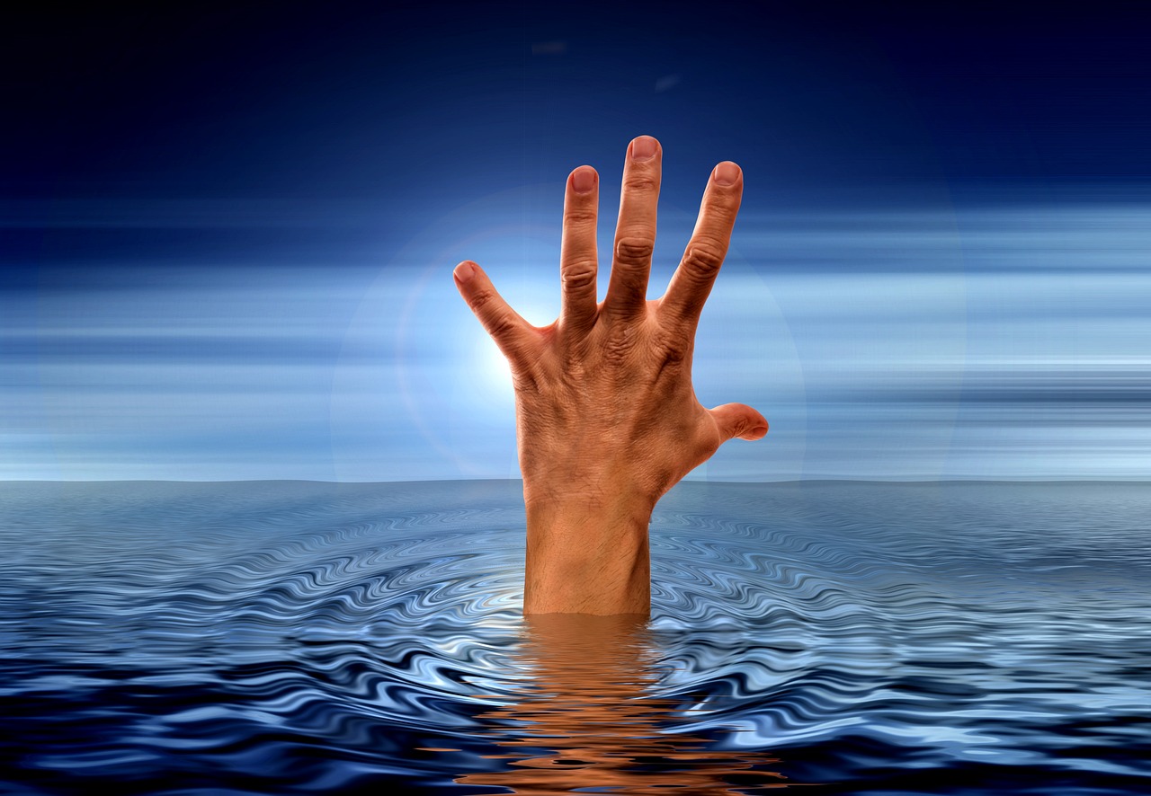 Eine Hand streckt sich hilfesuchend aus dem Wasser